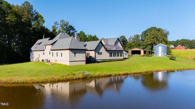 rear view of property featuring a water view and a lawn