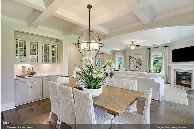 dining space featuring coffered ceiling, ceiling fan with notable chandelier, a fireplace, beam ceiling, and dark hardwood / wood-style flooring