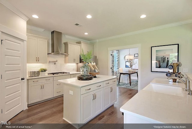 kitchen featuring stainless steel gas stovetop, a center island, sink, wall chimney exhaust hood, and dark hardwood / wood-style floors