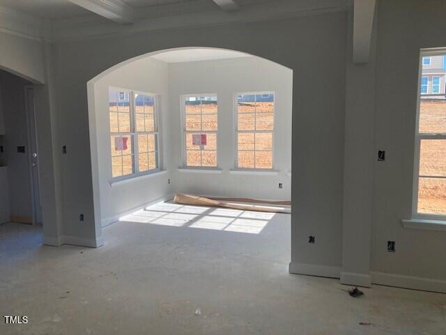 spare room featuring beam ceiling and a wealth of natural light