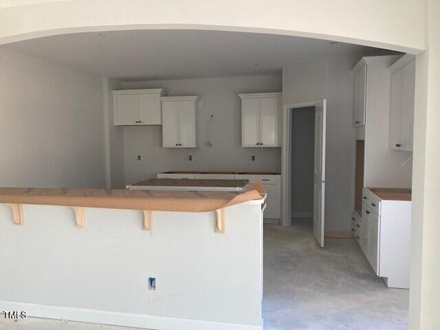 kitchen featuring a kitchen breakfast bar, kitchen peninsula, and white cabinets