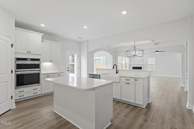 kitchen featuring white cabinetry, kitchen peninsula, a center island, sink, and appliances with stainless steel finishes