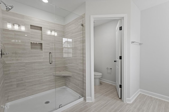 bathroom with a shower with door and toilet