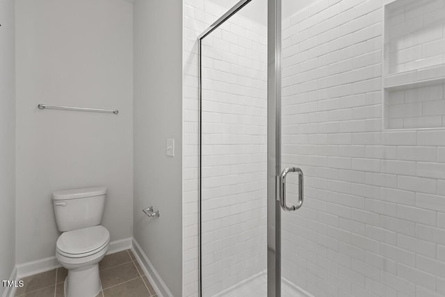 bathroom featuring a shower with shower door, toilet, and tile patterned floors