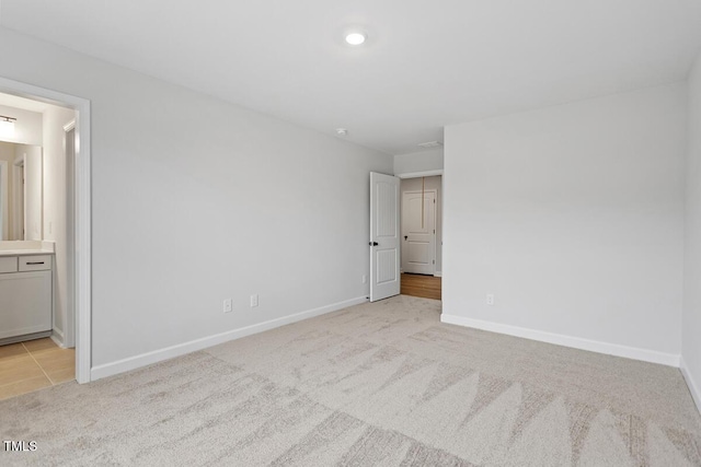 unfurnished bedroom with connected bathroom and light colored carpet