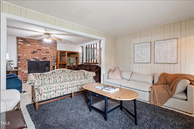 carpeted living room with wooden walls and ceiling fan