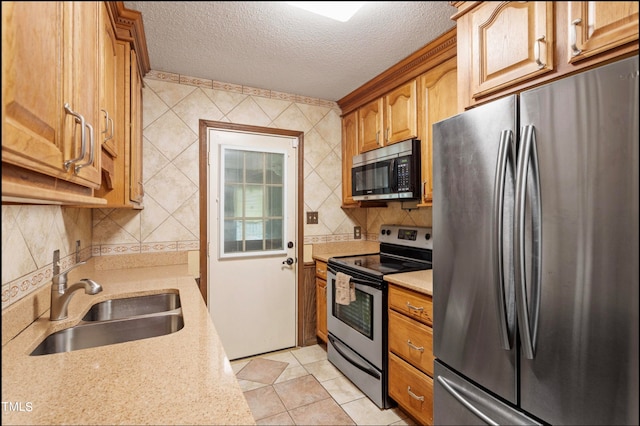 kitchen with a textured ceiling, appliances with stainless steel finishes, sink, and light tile patterned flooring