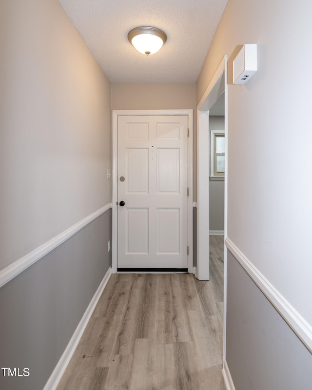 doorway to outside with a textured ceiling and light hardwood / wood-style flooring