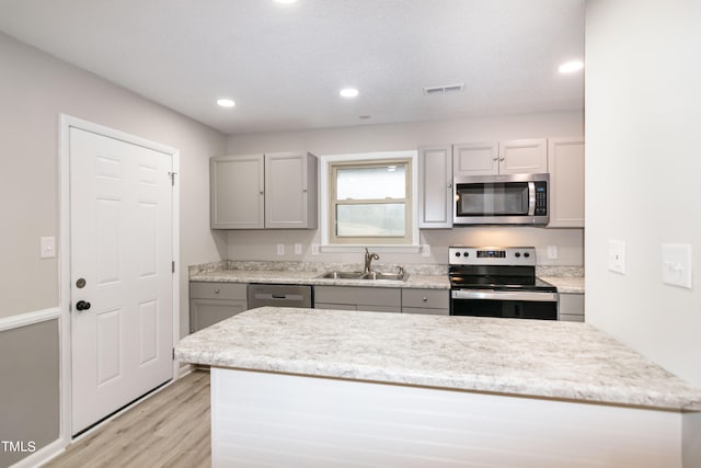 kitchen with gray cabinets, stainless steel appliances, light wood-type flooring, and sink