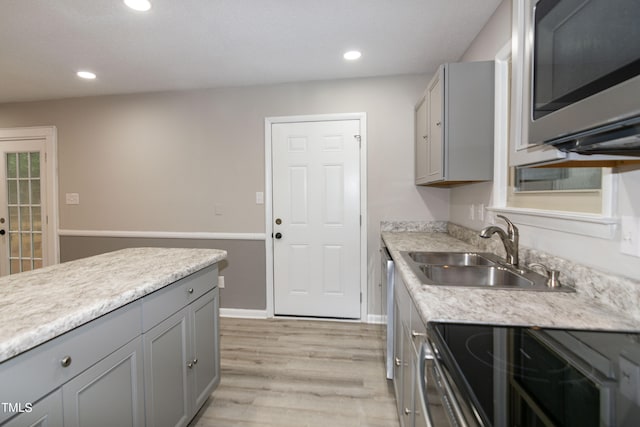 kitchen with gray cabinetry, light hardwood / wood-style floors, range, and sink