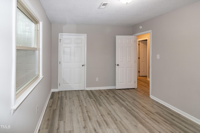 unfurnished bedroom with a textured ceiling and light hardwood / wood-style flooring