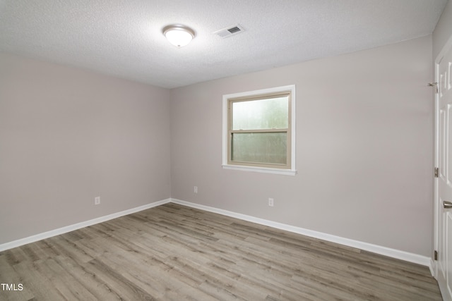 spare room featuring light wood-type flooring and a textured ceiling