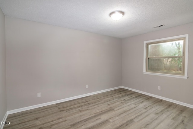 empty room with a textured ceiling and light wood-type flooring