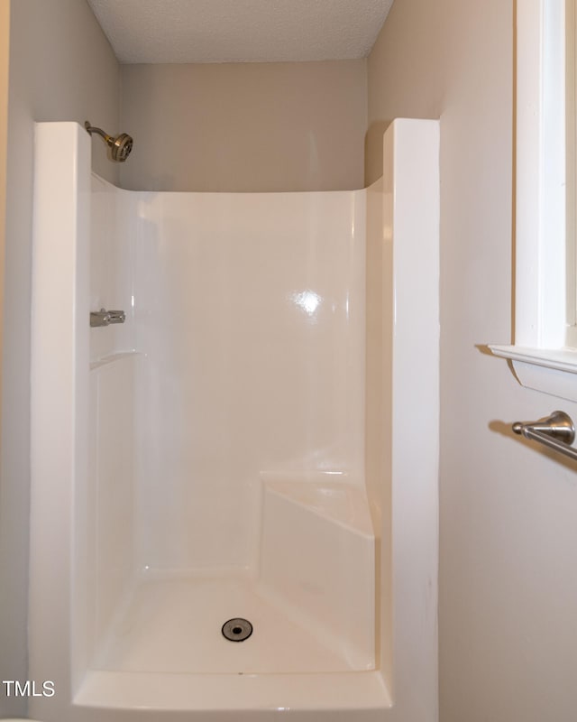 bathroom featuring a textured ceiling and a shower