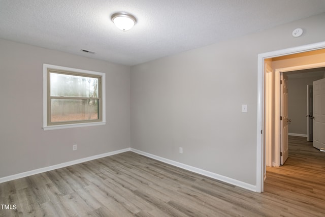 spare room featuring a textured ceiling and light hardwood / wood-style flooring