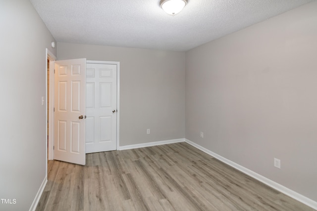 unfurnished room with a textured ceiling and light hardwood / wood-style floors