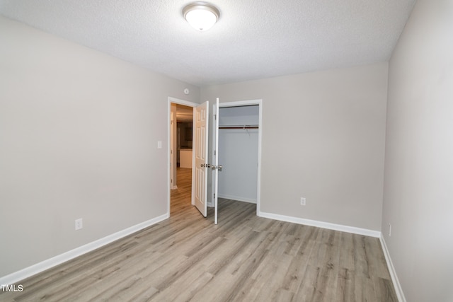 unfurnished bedroom with a textured ceiling, light hardwood / wood-style flooring, and a closet