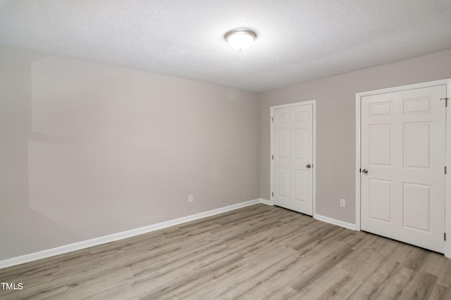 unfurnished bedroom with light wood-type flooring and a textured ceiling