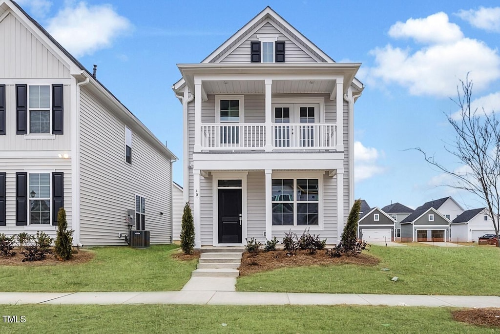 view of front of house with central AC unit, a balcony, and a front yard