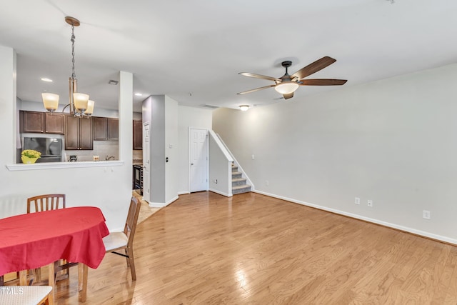 dining area featuring ceiling fan with notable chandelier and light hardwood / wood-style floors