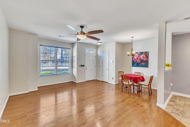 interior space featuring ceiling fan with notable chandelier and light hardwood / wood-style flooring