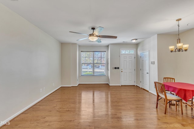 foyer entrance with ceiling fan with notable chandelier and light hardwood / wood-style flooring