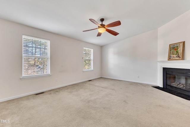 unfurnished living room featuring carpet flooring, plenty of natural light, and ceiling fan