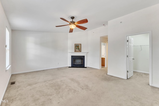 unfurnished living room with light colored carpet, a wealth of natural light, and ceiling fan