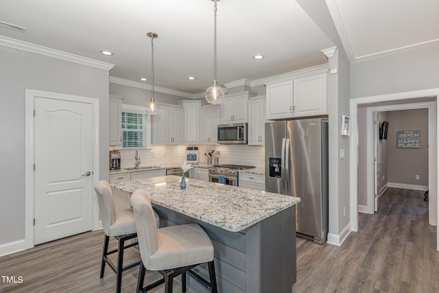 kitchen with a kitchen island, stainless steel appliances, dark wood-type flooring, sink, and pendant lighting