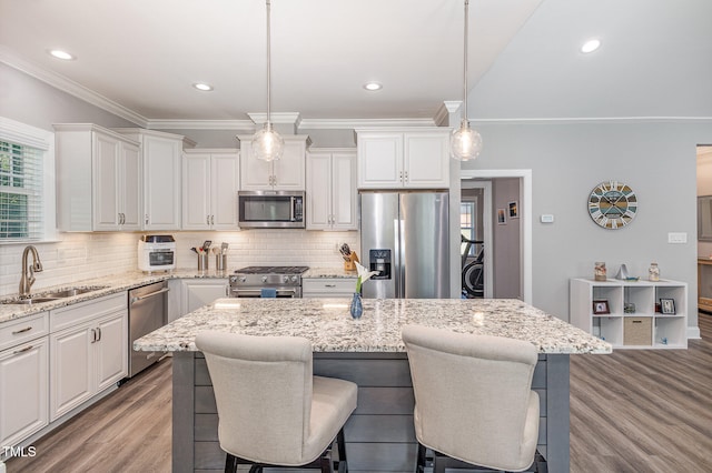 kitchen with a kitchen island, light hardwood / wood-style flooring, decorative light fixtures, white cabinets, and appliances with stainless steel finishes