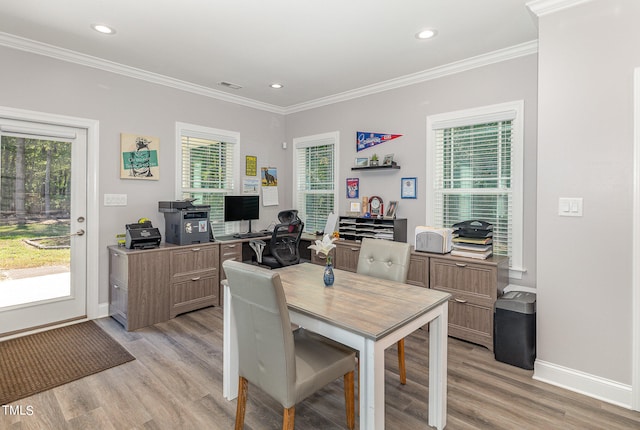 dining space with light wood-type flooring, crown molding, and a wealth of natural light