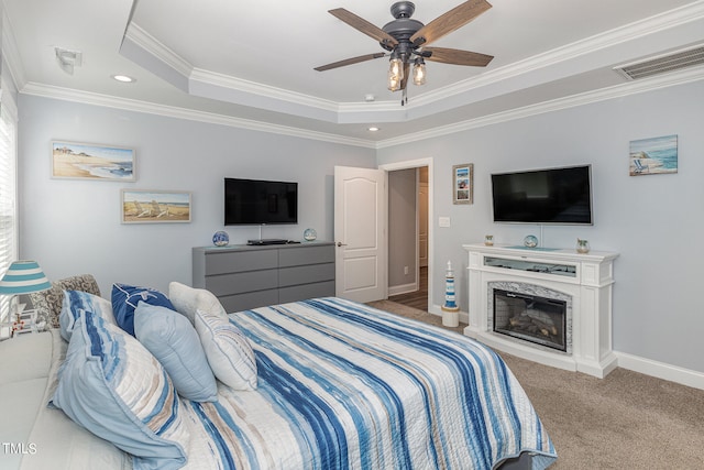 carpeted bedroom featuring ornamental molding, a high end fireplace, ceiling fan, and a tray ceiling