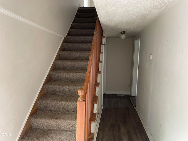 stairway featuring wood-type flooring and a textured ceiling