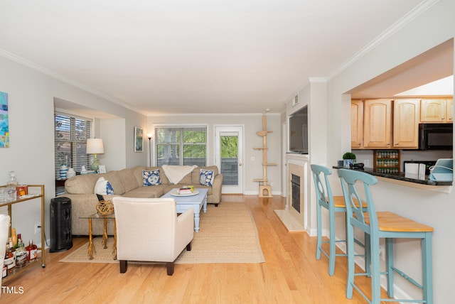 living room featuring light hardwood / wood-style flooring, crown molding, and a wealth of natural light