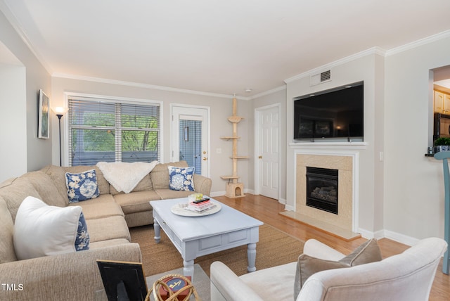 living room featuring light wood-type flooring, ornamental molding, and a high end fireplace