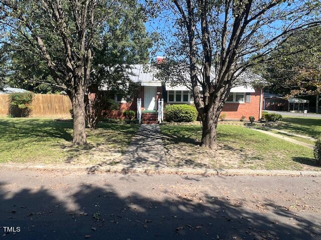 view of front facade featuring a front yard, brick siding, and fence