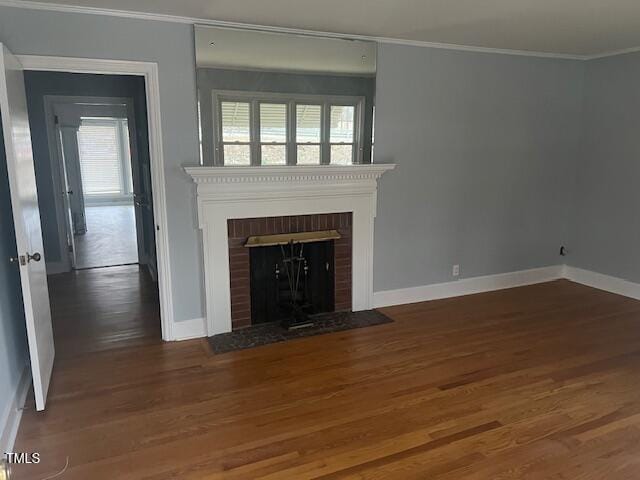 unfurnished living room with baseboards, a fireplace, wood finished floors, and crown molding