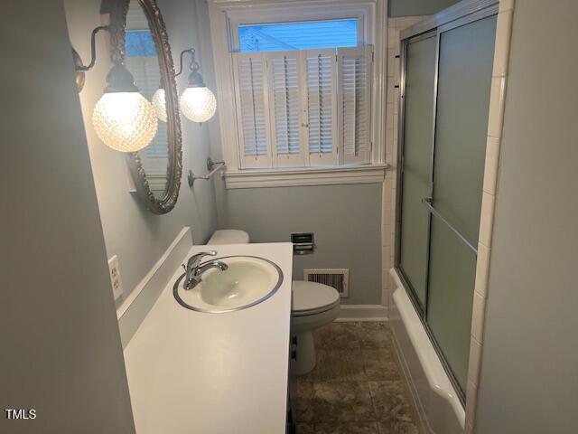 full bathroom featuring visible vents, toilet, combined bath / shower with glass door, vanity, and baseboards