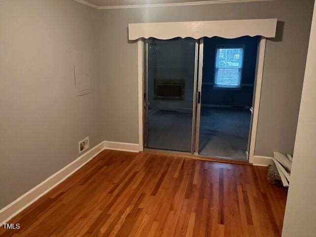 spare room with crown molding, baseboards, and wood finished floors