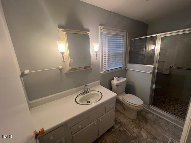 full bathroom with toilet, a stall shower, and vanity