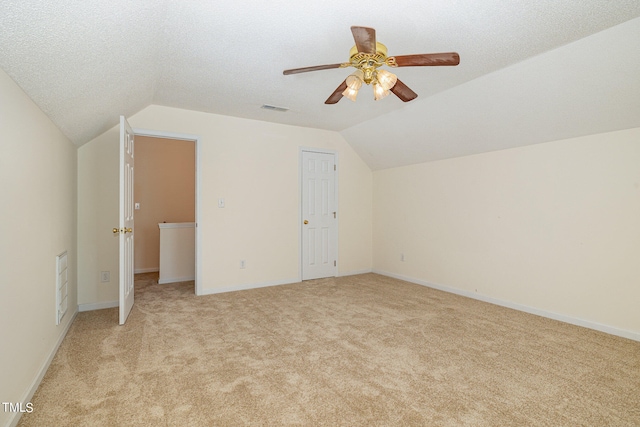 additional living space featuring a textured ceiling, vaulted ceiling, light colored carpet, and ceiling fan