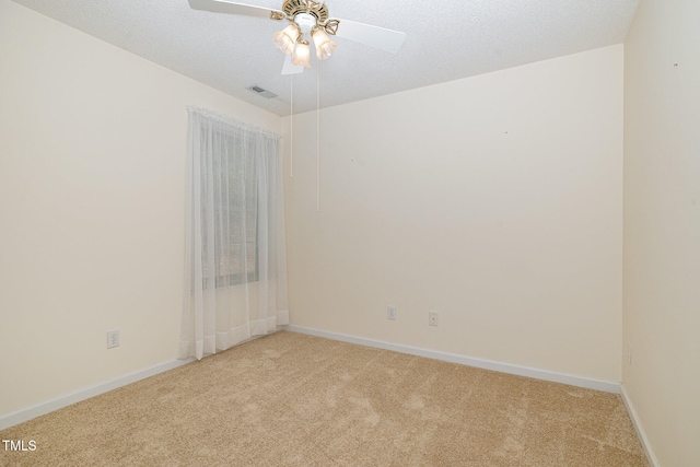 spare room featuring a textured ceiling, light colored carpet, and ceiling fan