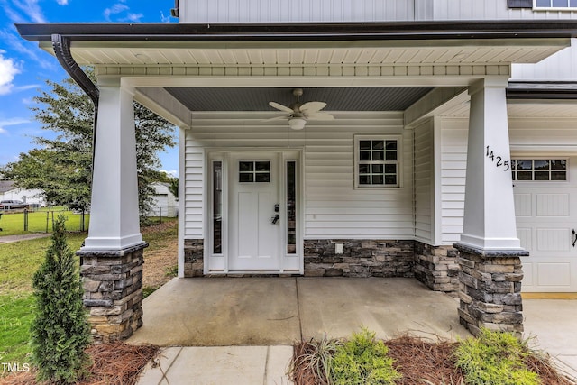 view of exterior entry featuring a garage, ceiling fan, and covered porch