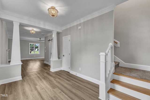 interior space with ornamental molding, ceiling fan, hardwood / wood-style floors, and a barn door