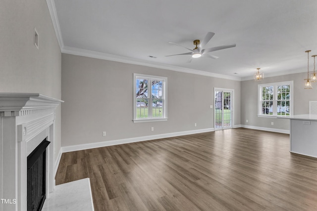 unfurnished living room with ceiling fan with notable chandelier, crown molding, and dark wood-type flooring