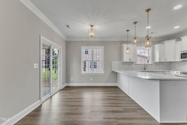 kitchen with pendant lighting, dark hardwood / wood-style floors, white cabinets, electric range oven, and backsplash