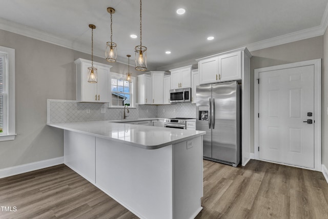 kitchen featuring white cabinets, hanging light fixtures, kitchen peninsula, hardwood / wood-style flooring, and appliances with stainless steel finishes