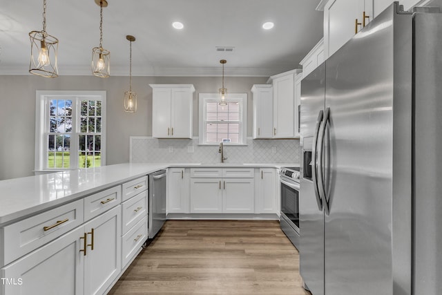 kitchen with appliances with stainless steel finishes, light hardwood / wood-style floors, white cabinetry, and pendant lighting