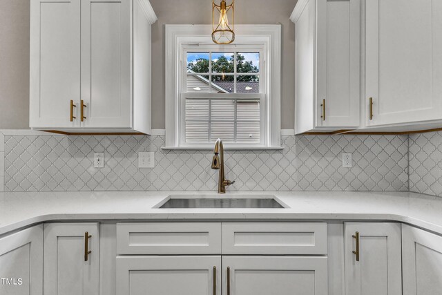 kitchen with white cabinetry, hanging light fixtures, tasteful backsplash, and sink