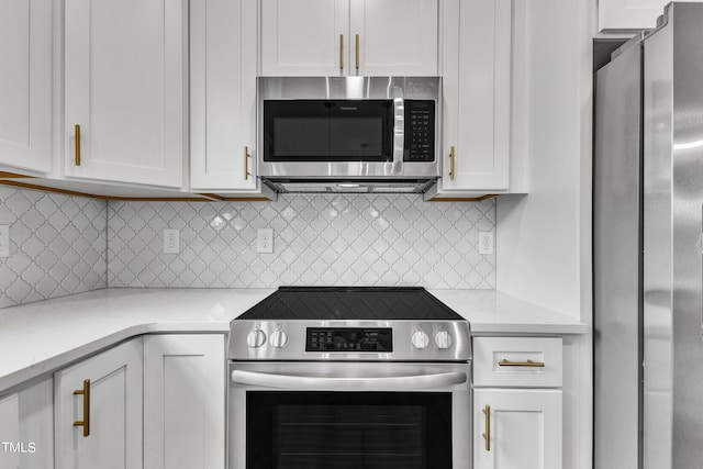 kitchen featuring white cabinets, appliances with stainless steel finishes, backsplash, and light stone countertops